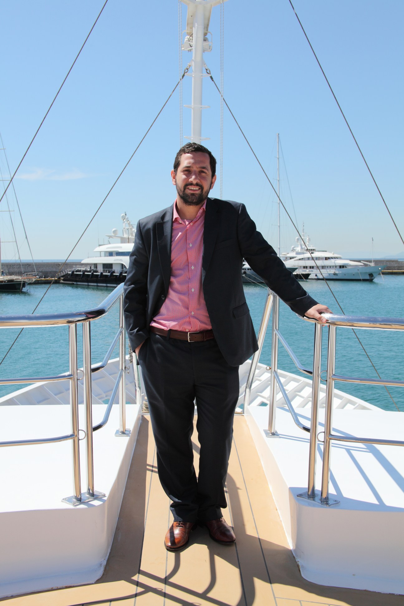 Filippos Venetopoulos standing on the deck of a yacht in a Greek harbour.