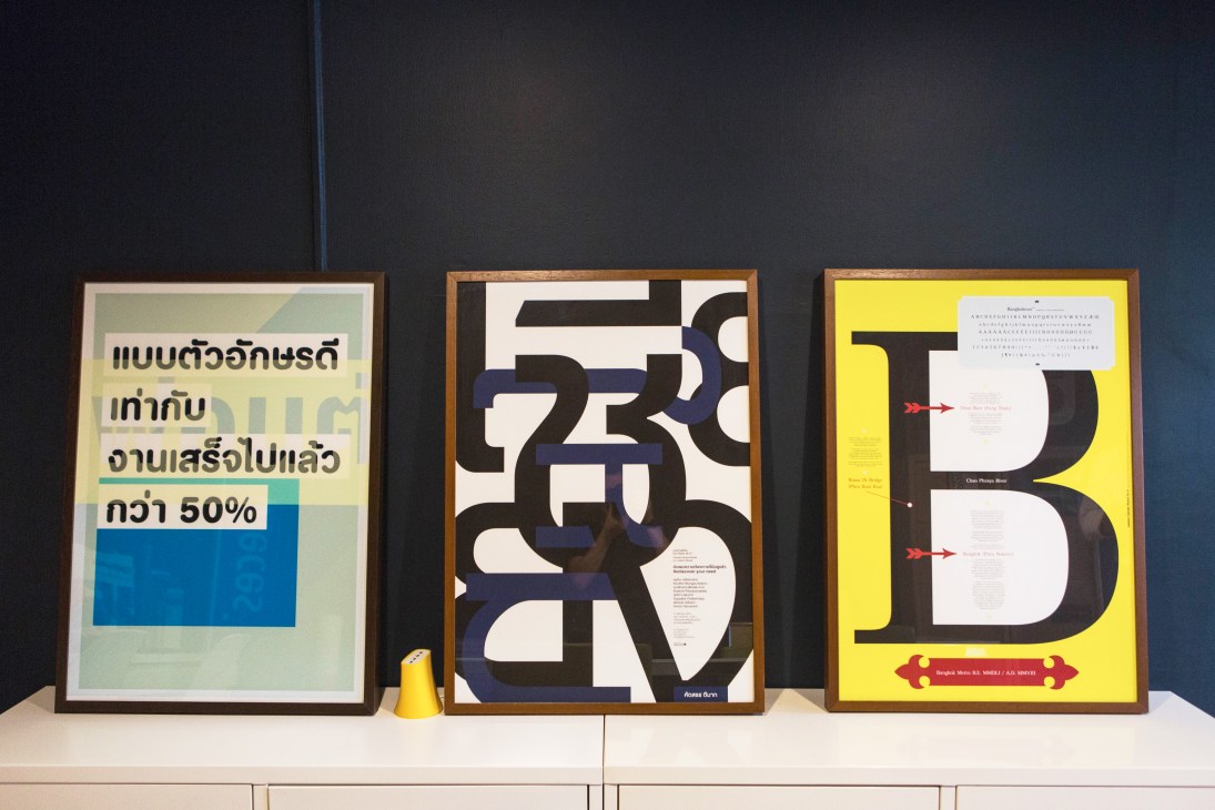Three framed typography posters displayed on a white shelf against a dark wall