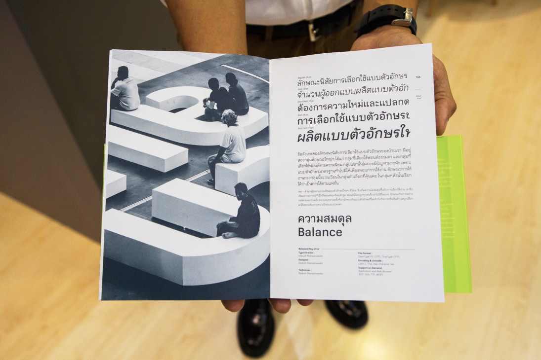 Hands holding open magazine spread showing geometric architectural photography and Thai text titled Balance