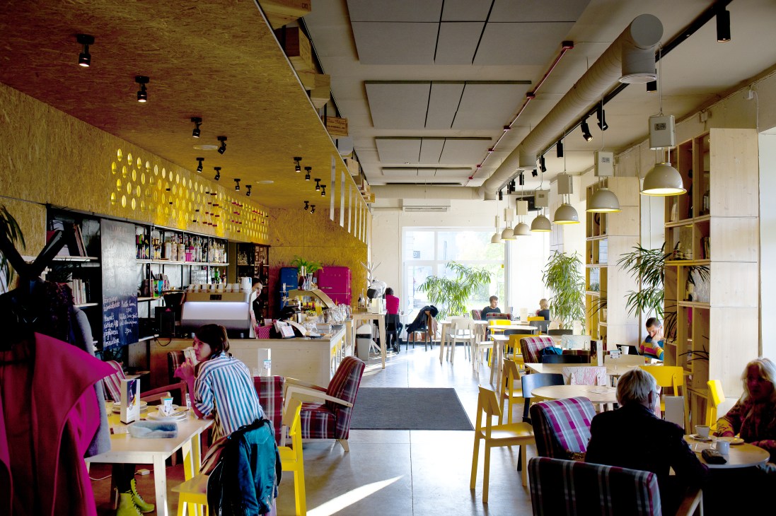 Bright modern café interior with yellow walls, colorful chairs, and pendant lighting at Reval Café.