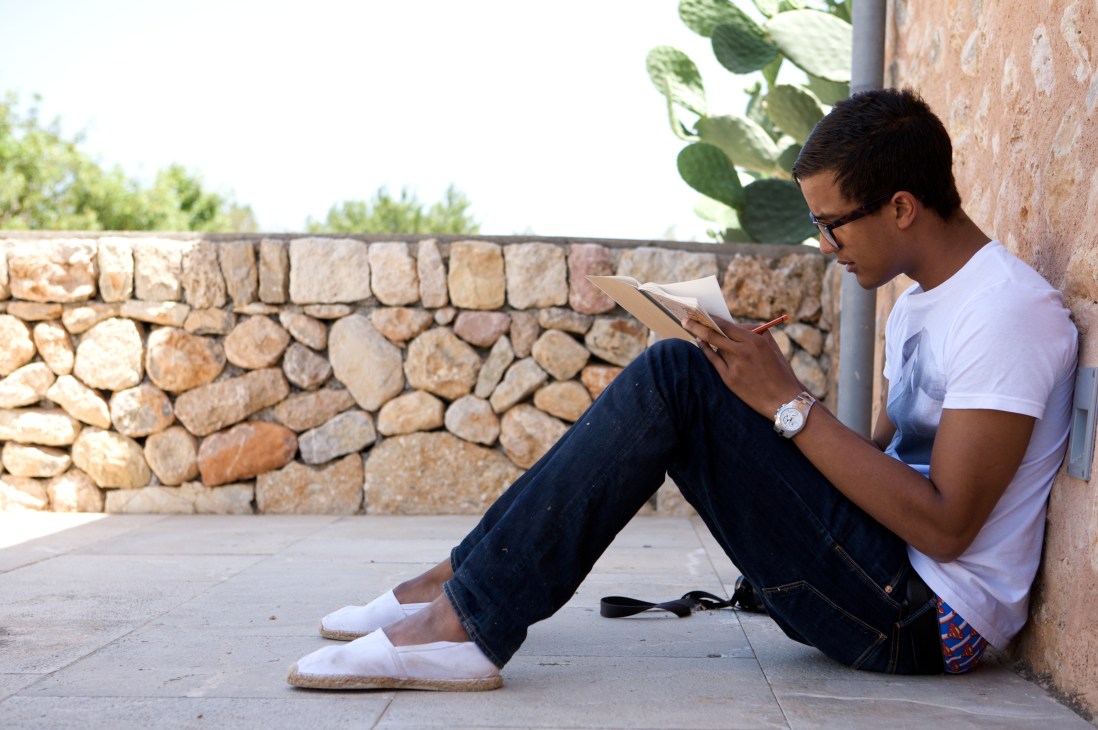 Winning student Mansour Badjoko wa Lileko sits reading against a stone wall at Son Forteza.