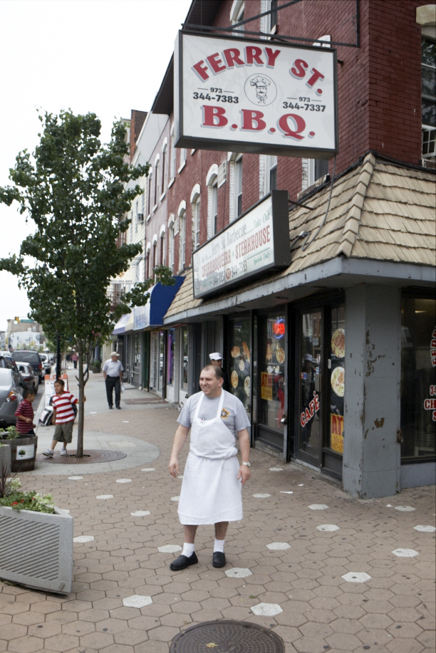 A shopkeeper stands outside Ferry Street B.B.Q. restaurant in downtown Newark.