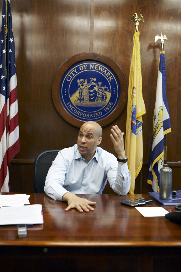 Cory Booker sits at his desk in Newark City Hall, gesturing while speaking during an interview.