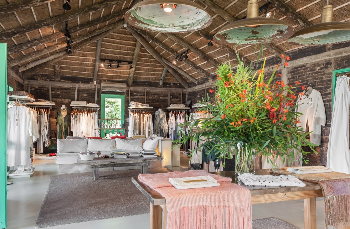 Interior of El Canuto shop with clothing racks, wooden beams, and flowers.