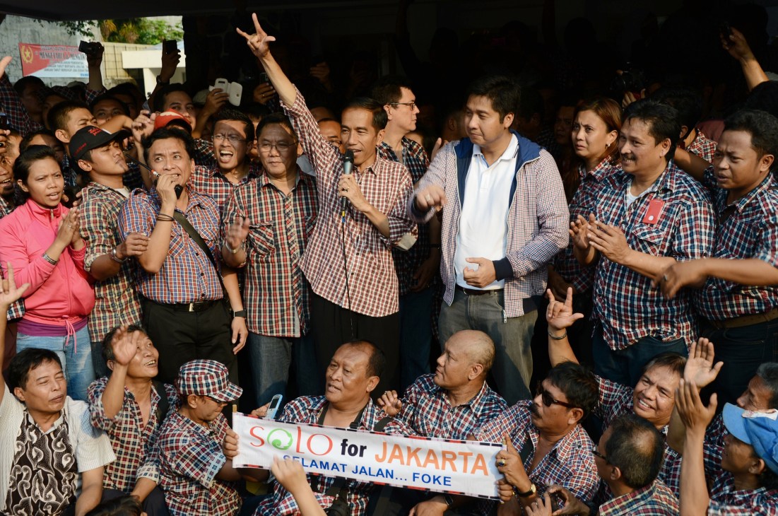 Joko Widodo surrounded by supporters wearing red and white checkered shirts at a campaign rally in Jakarta.