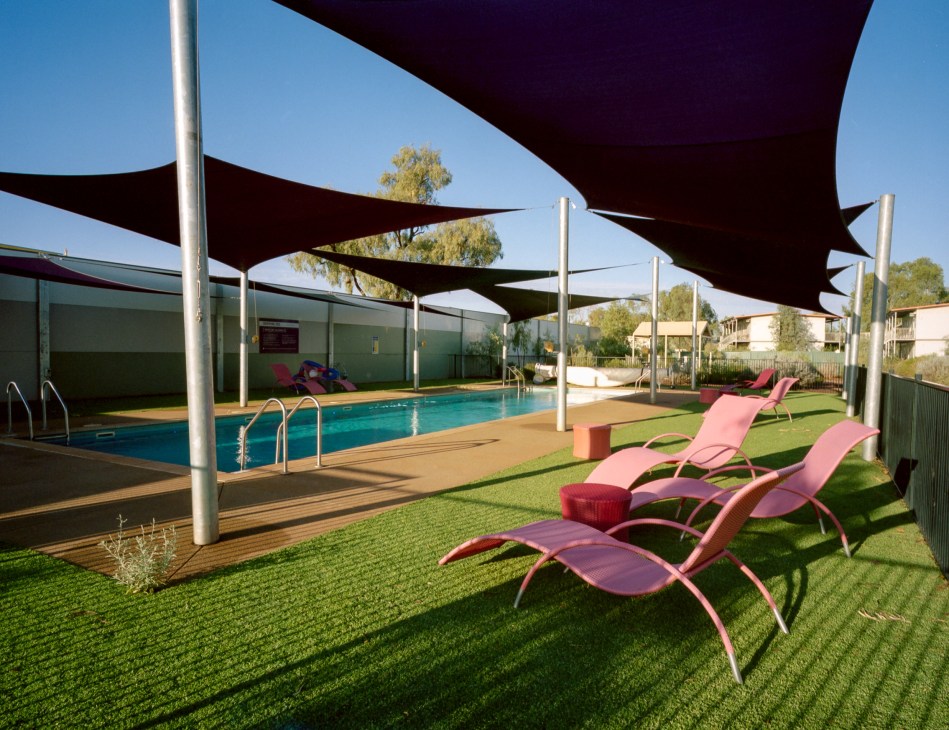 Swimming pool with pink loungers, black shade sails, and manicured lawn at the Capricorn roadhouse in Western Australia.