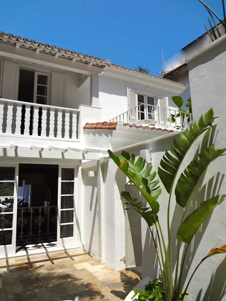 White colonial-style house with terracotta roof tiles, balconies and tropical plants in Rio de Janeiro.