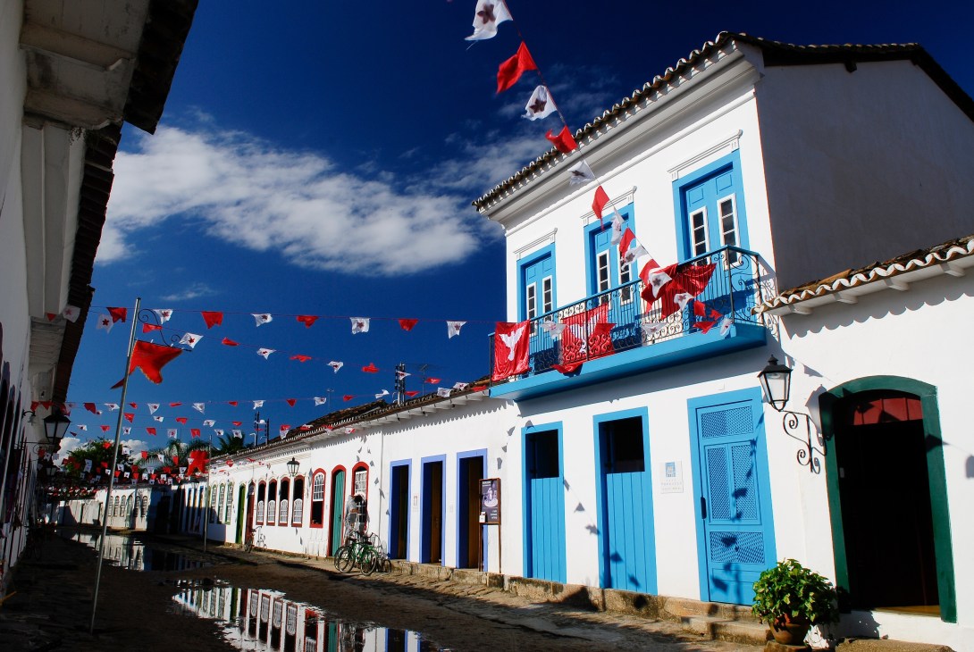 Colonial-style white building with blue doors and shutters decorated with red and white flags.