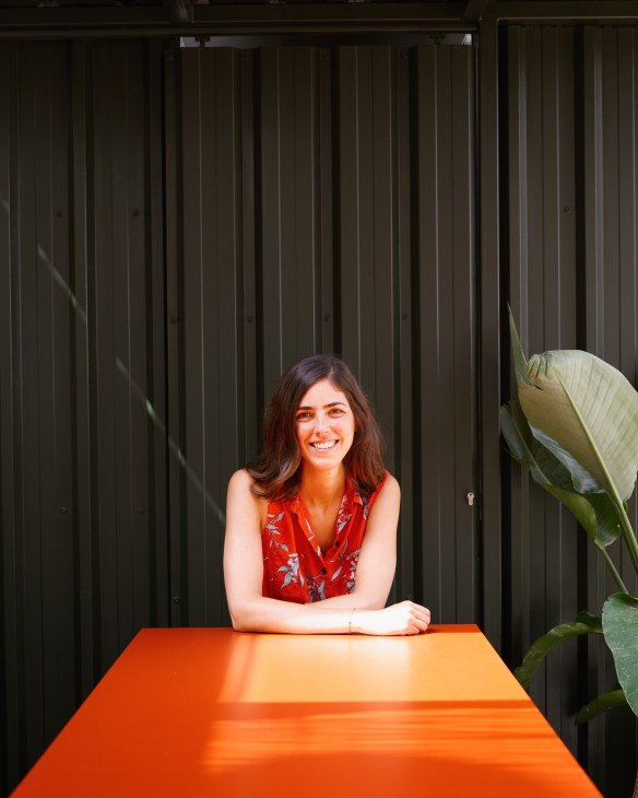 Inés Miró-Sans, owner of Casa Bonay hotel in Barcelona, smiling at an orange table against a dark corrugated backdrop.