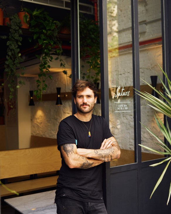 Marcos Bartolomé, owner of Satan's Coffee Corner, stands outside his storefront with arms crossed.