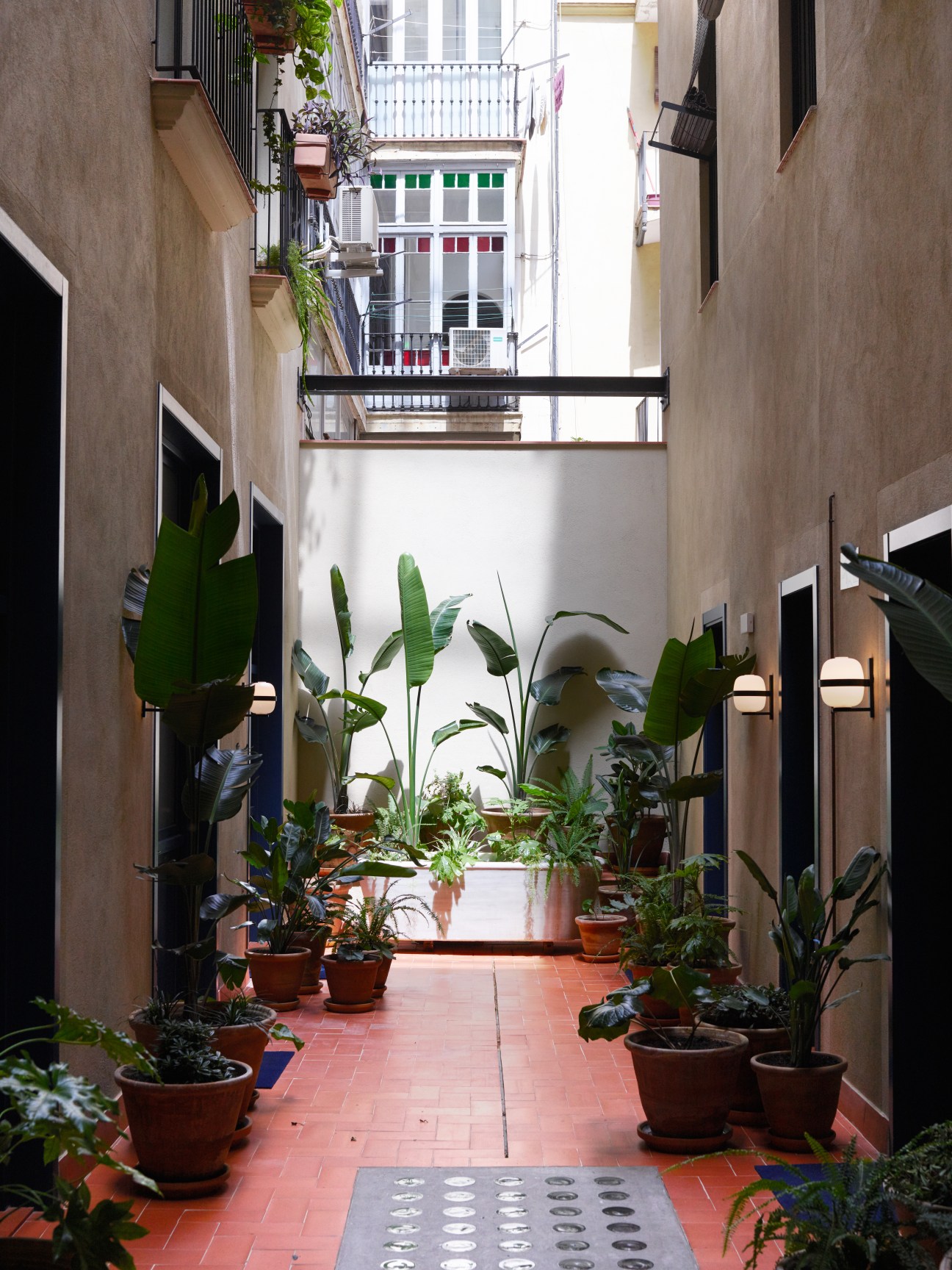 Casa Bonay's interior courtyard with potted plants lining a red-tiled pathway and colorful windows above.