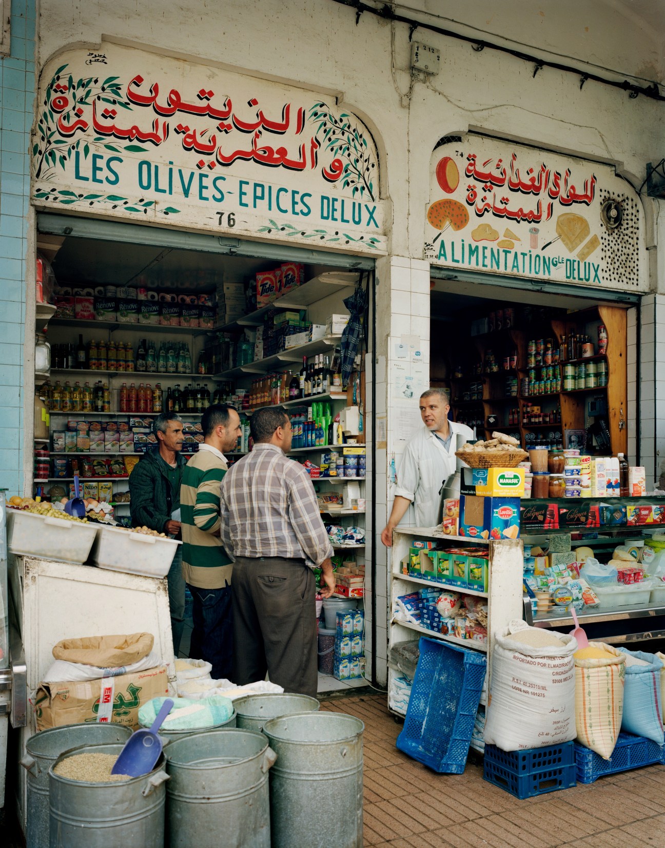 A shop in Le Marché Central displaying olives, spices and food items with Arabic and French signage.