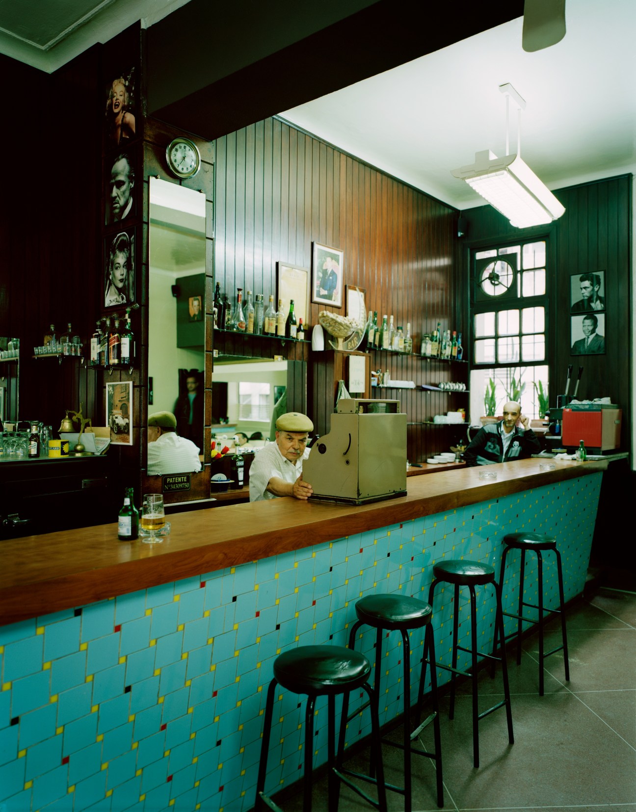 Bar Atomic interior with turquoise tiled counter, vintage Hollywood portraits, and bartender in Casablanca.