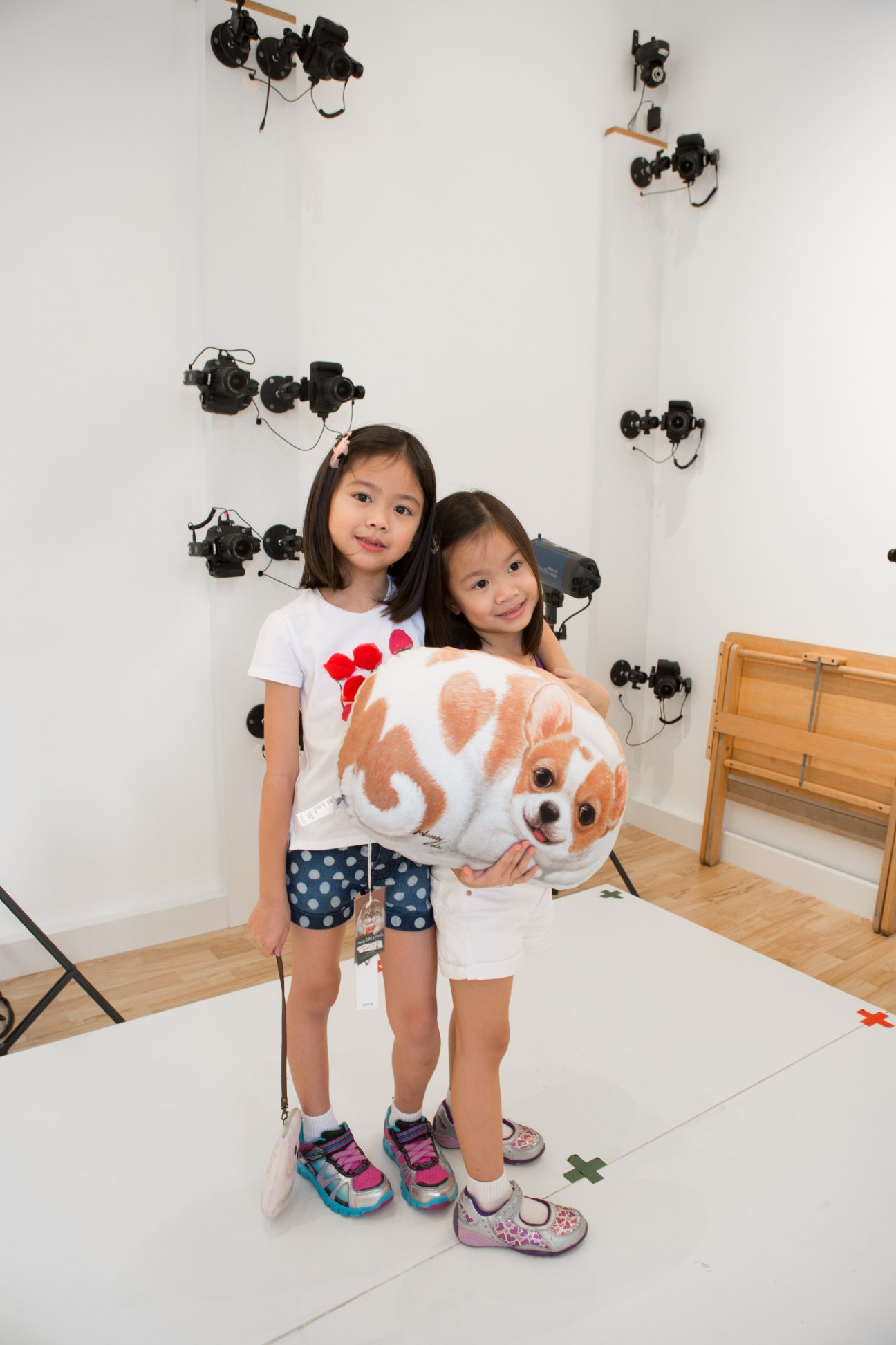 Two young girls holding a 3D-printed lifelike model of an orange and white dog in The Barkyard's 3D-printing studio.