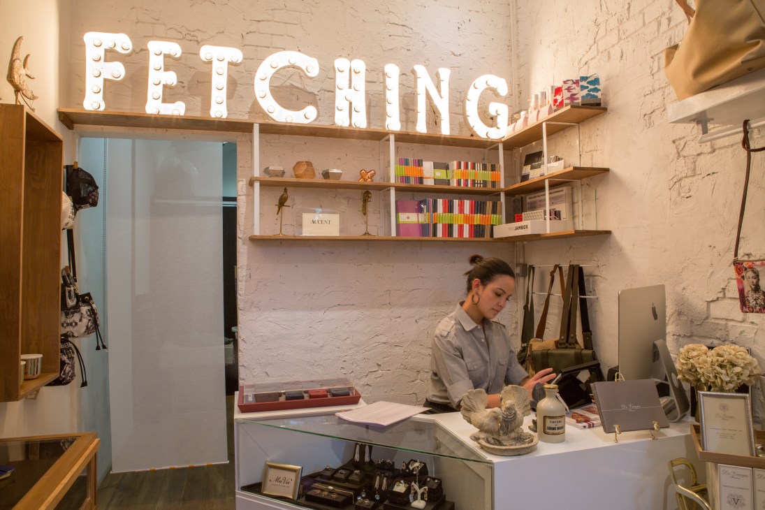 Interior of Fetching boutique shop with illuminated signage and staff member at counter