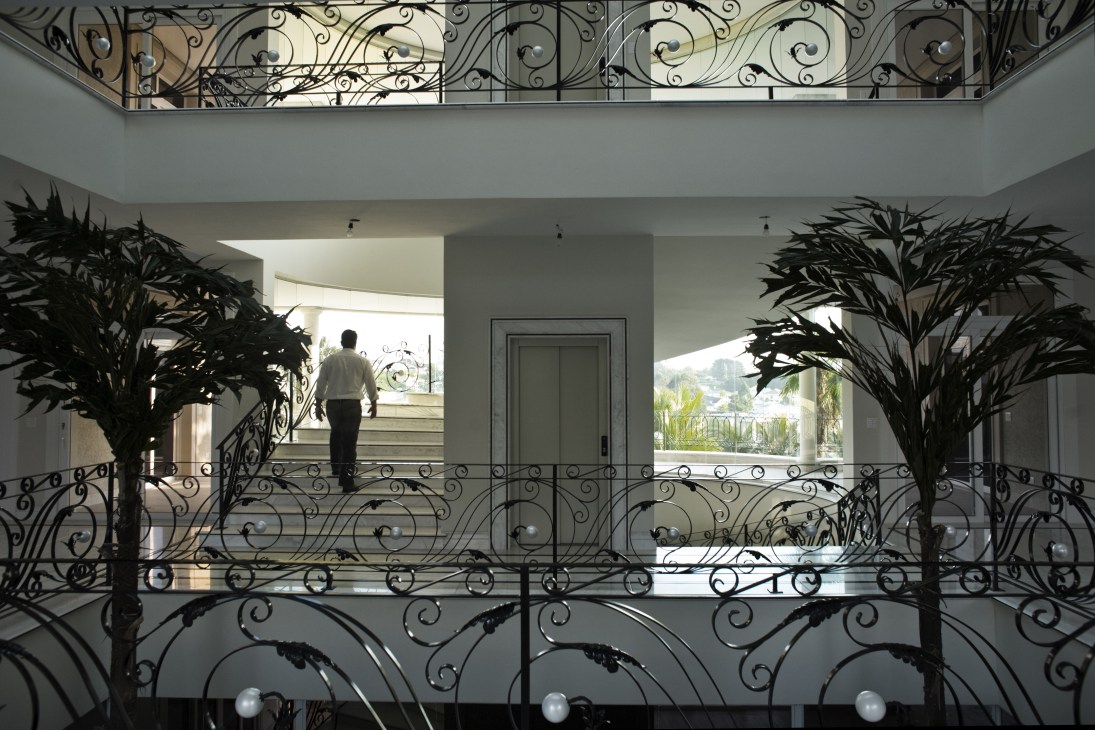 Interior of a luxury home showing ornate iron railings and a man walking on an upper level balcony.