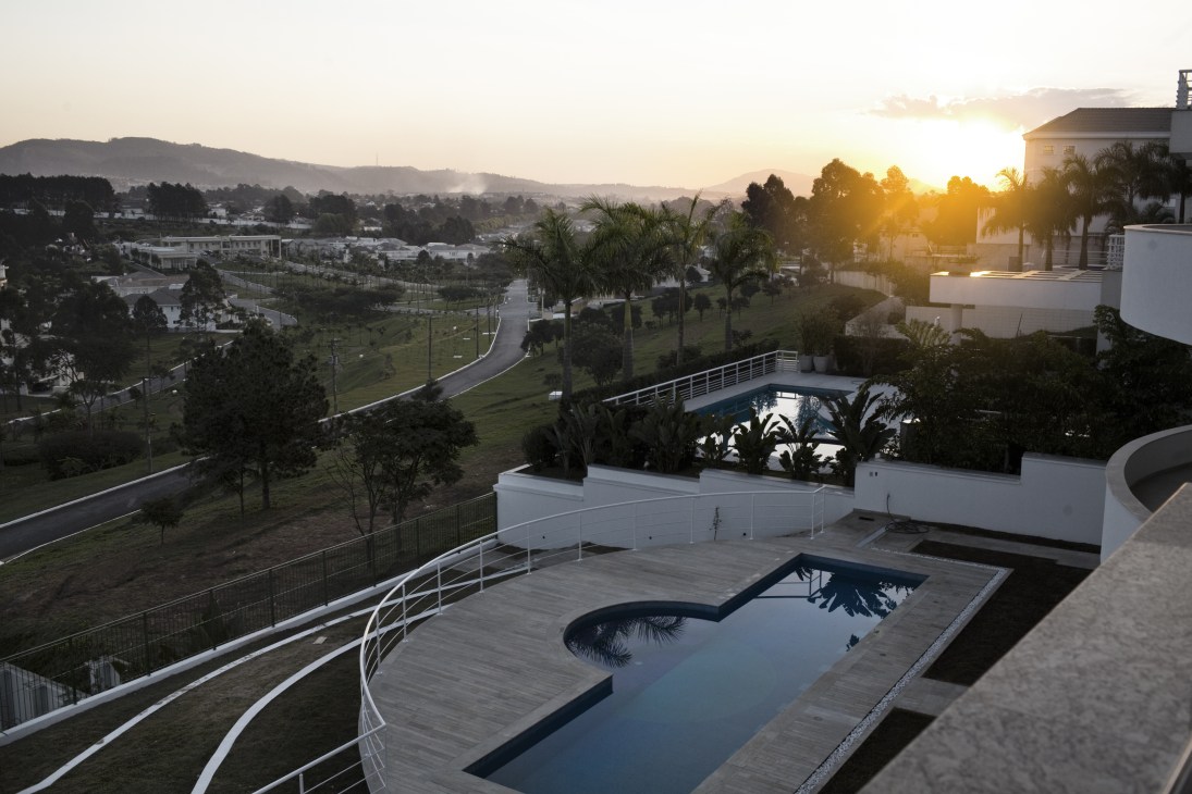 Sunset view over Tambore 2 gated community showing white houses, swimming pools, manicured lawns and palm trees with mountains in distance.