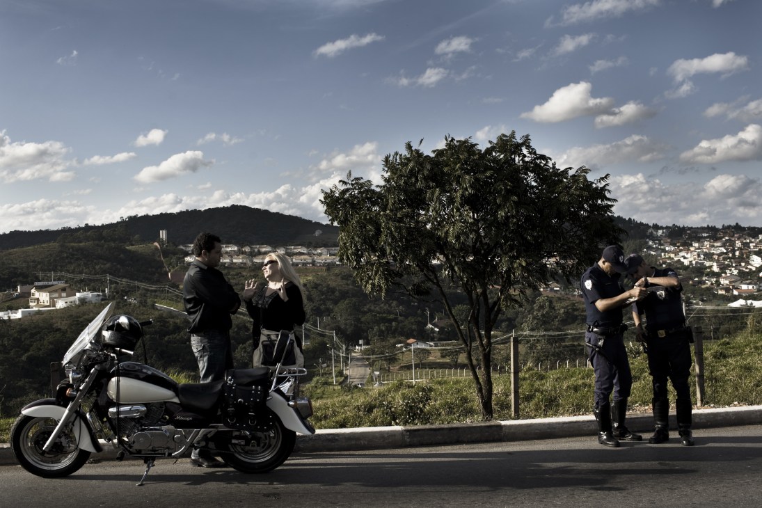 Police officers stop a couple on a motorcycle during a traffic enforcement operation in AlphaVille.