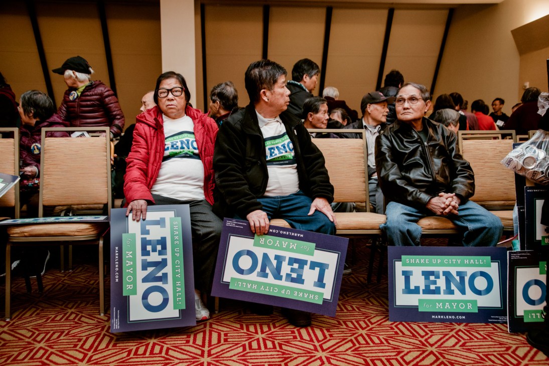 Supporters holding campaign signs for Mark Leno's mayoral campaign at an indoor event.
