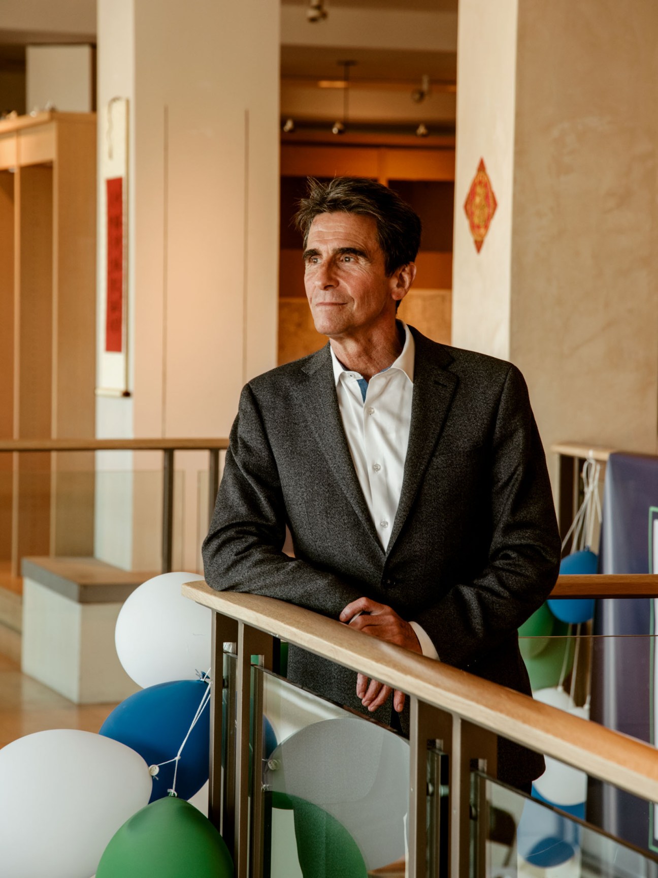 Mark Leno, mayoral candidate, standing at a railing in an interior space with modern decor.