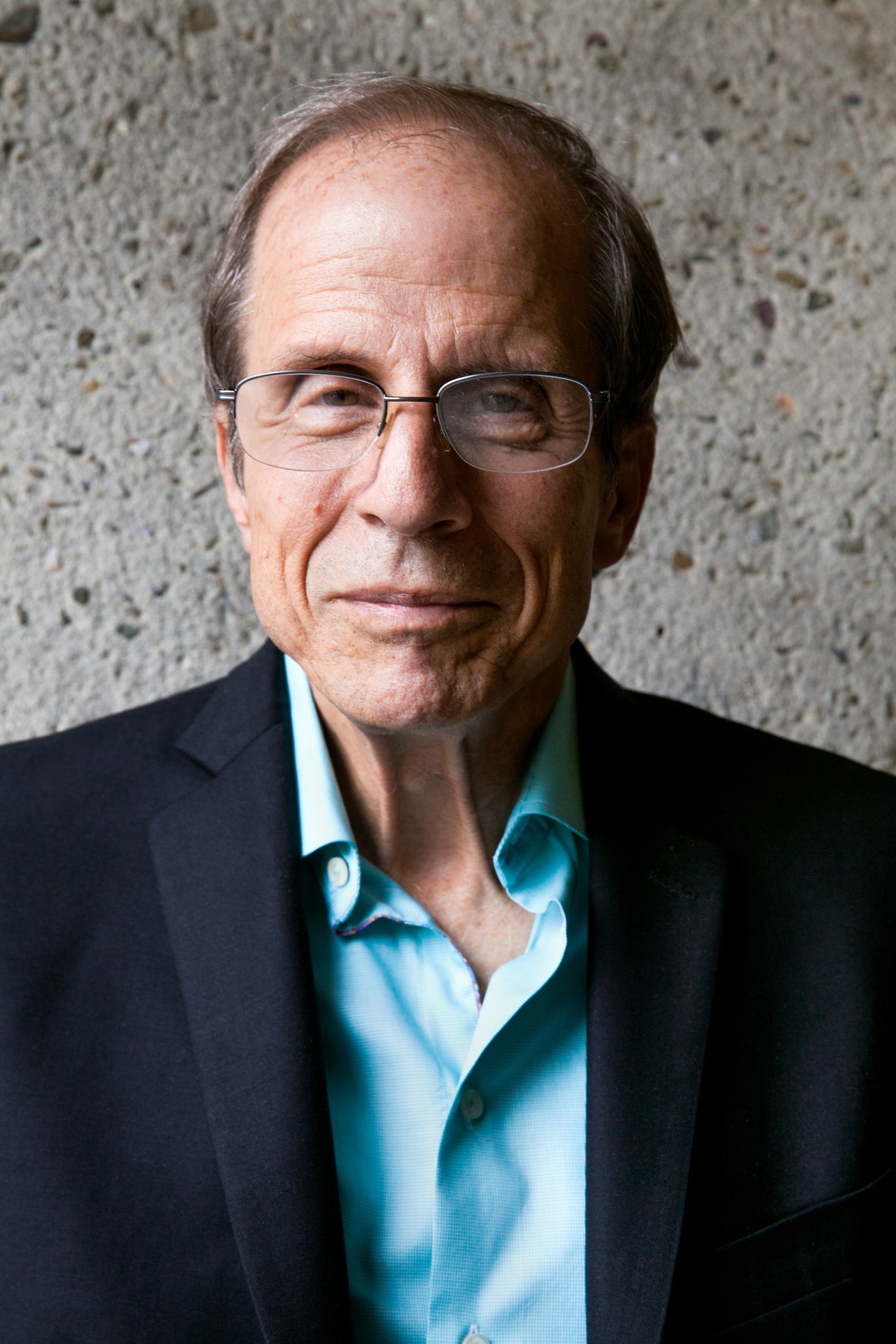 Michael Krasny, presenter of Forum on KQED public radio, wearing glasses and a blue shirt with dark blazer.