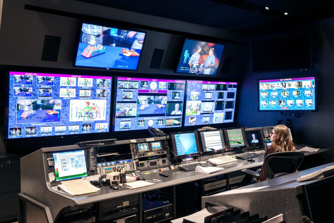 KQED TV control room with multiple screens displaying broadcast content and a technician at the console.