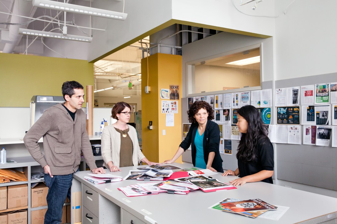 Mother Jones staff members gathered around a table reviewing magazine layouts and content in their office.