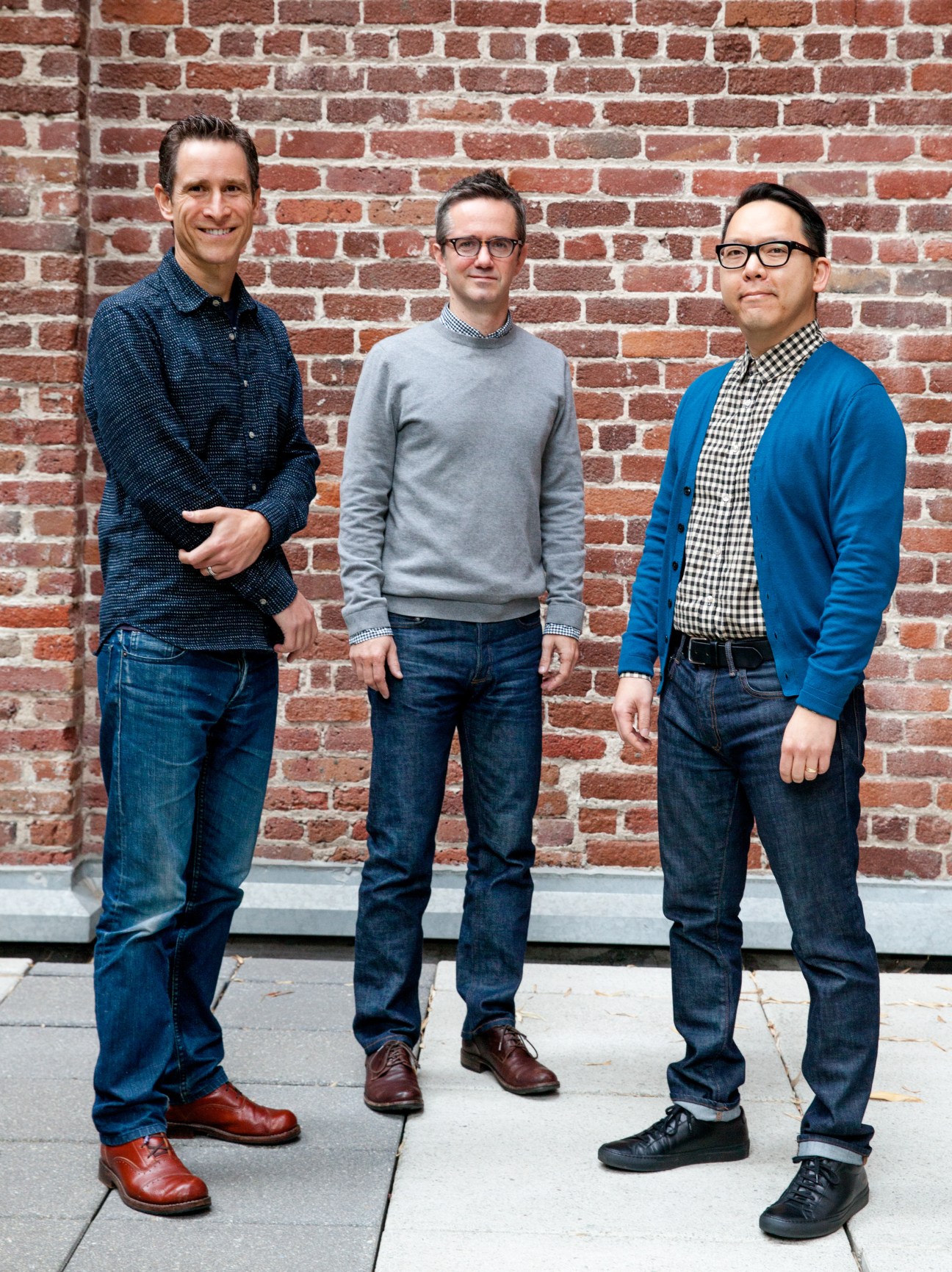 Three men stand against a red brick wall: Ghas Edwards, Douglas McGray and Leo Jung of The California Sunday Magazine.