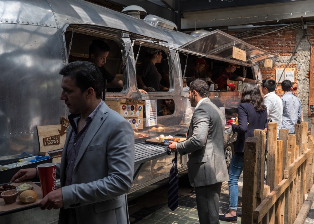 Customers queue at Pinche Gringo BBQ's silver aluminum food trailer in Mexico City