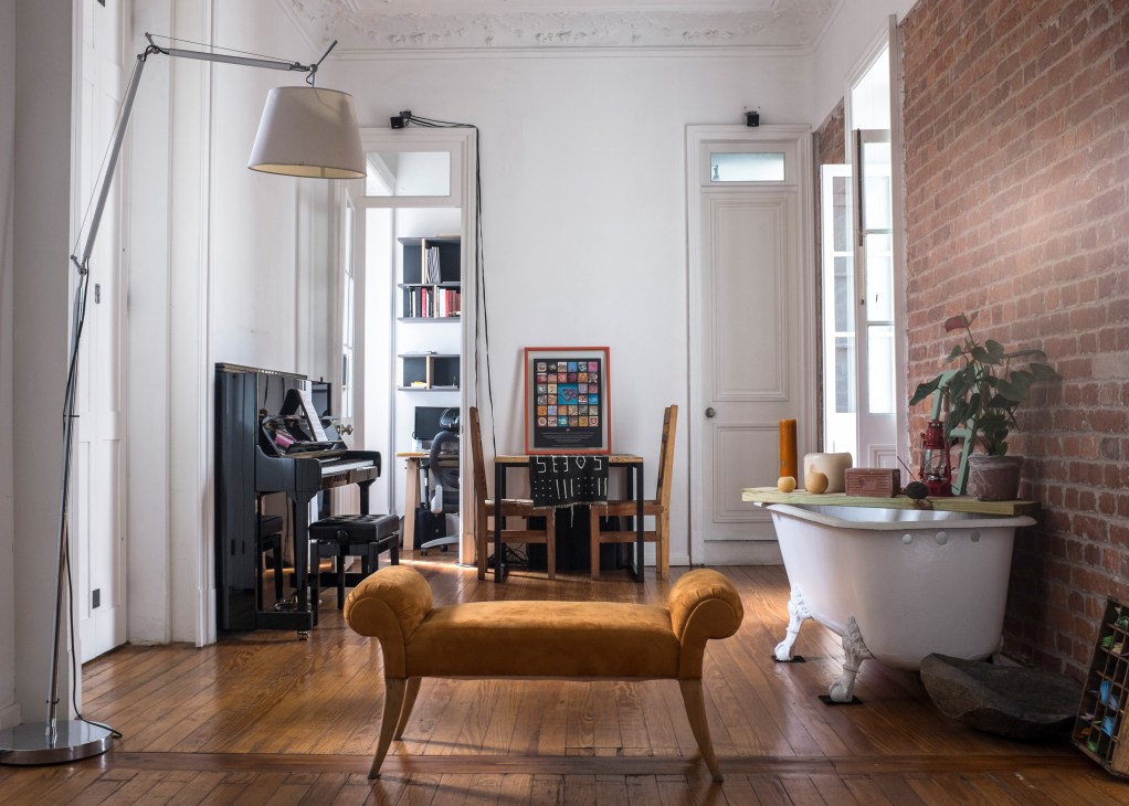Interior of Martin's apartment showing exposed brick wall, wooden floors, arc lamp, and eclectic furnishings.
