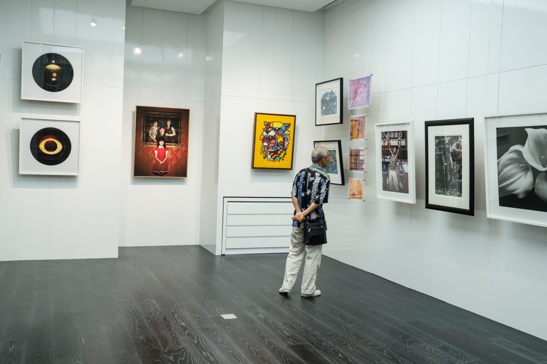 Visitor viewing contemporary artworks displayed on white walls in a gallery space.