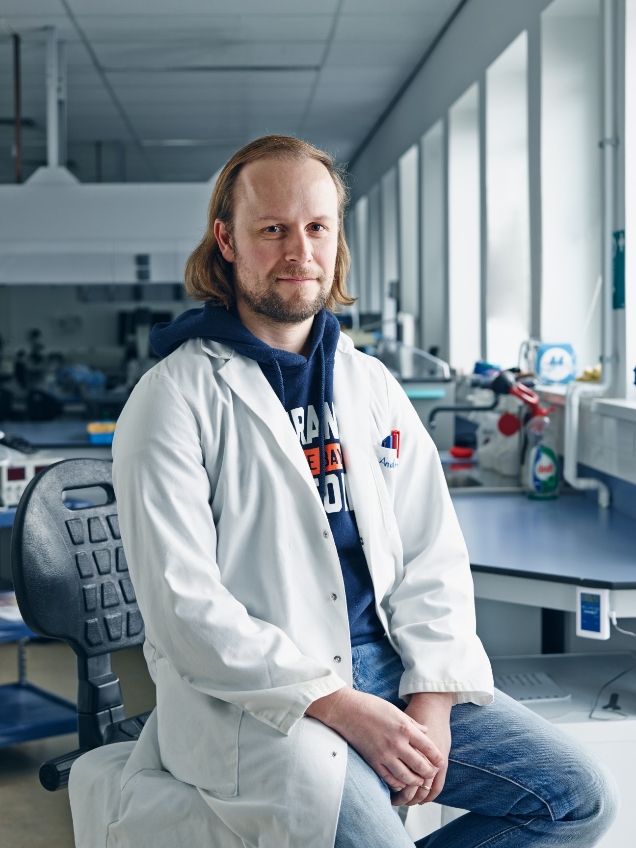Andreas Elsaesser, wearing a white lab coat, sits in a modern ESA laboratory at Estec.