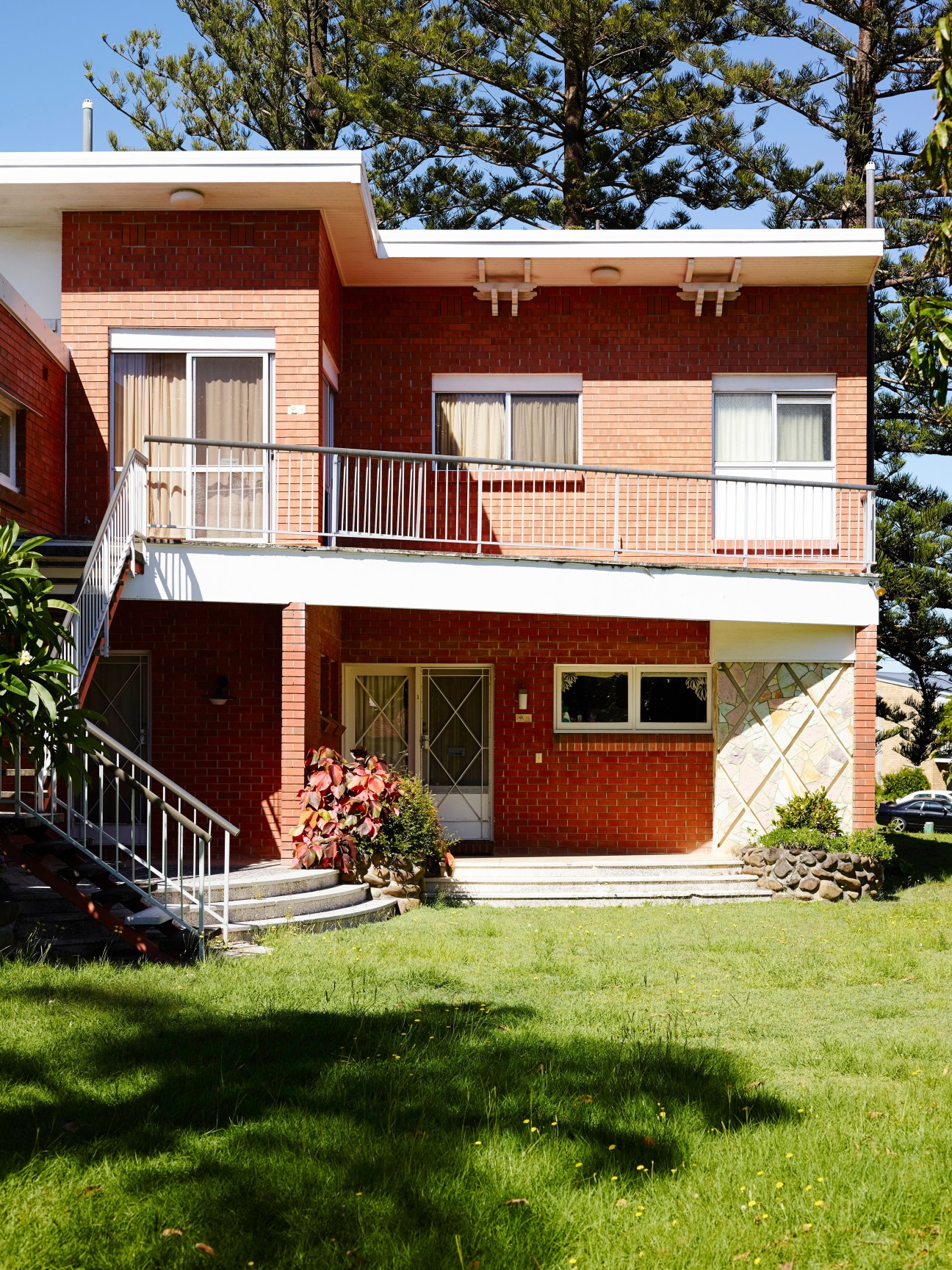 Mid-century modern brick and timber beach house with white trim and balconies on Paradise Island.