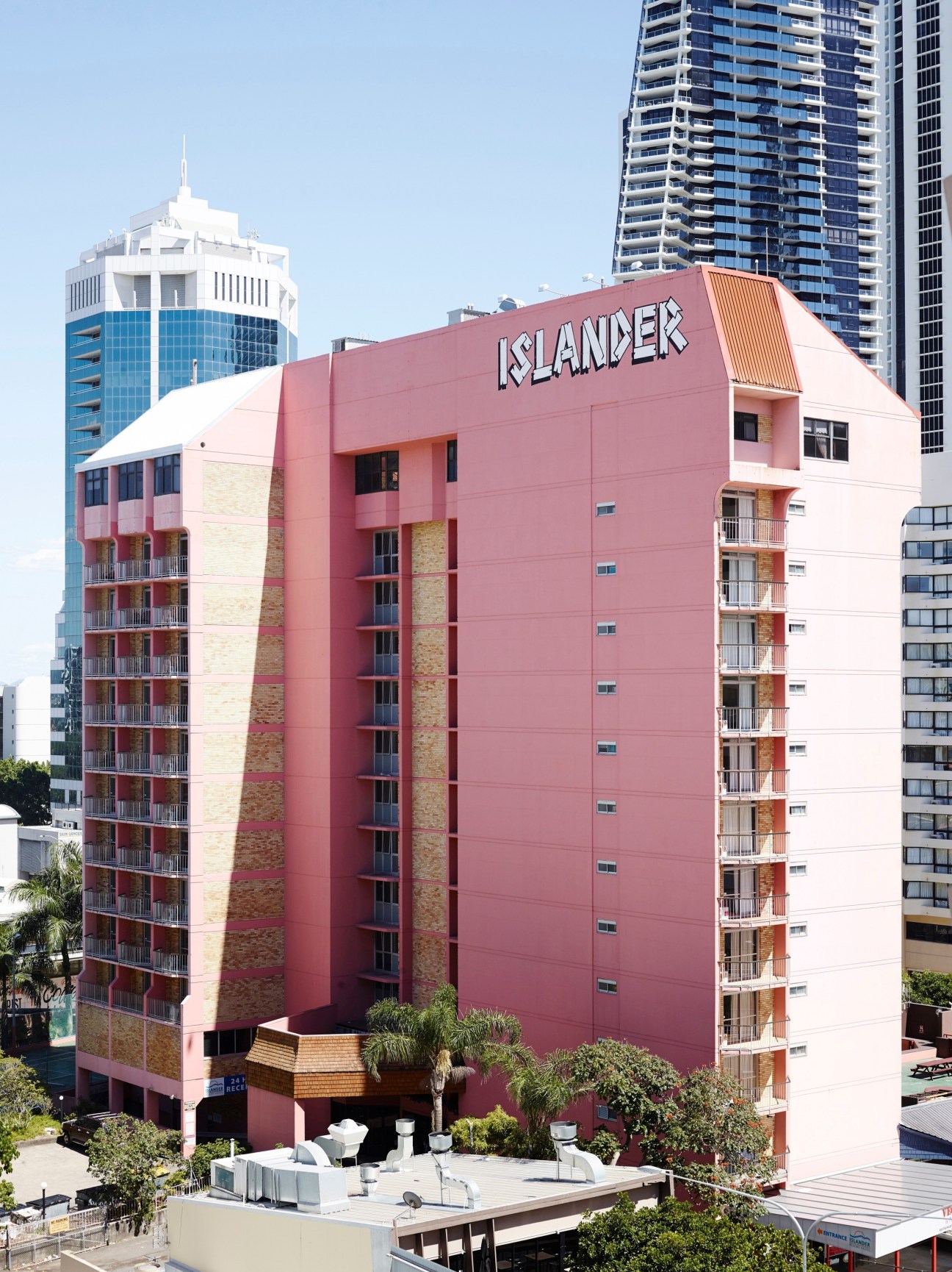Pink mid-century Islander Resort apartment building in Surfers Paradise with modern high-rises behind.