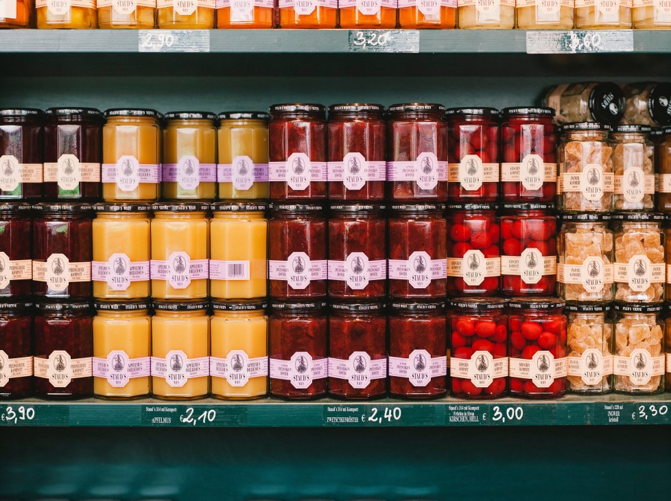 Shelves of Staud's preserves in glass jars with colorful labels arranged by variety and color.