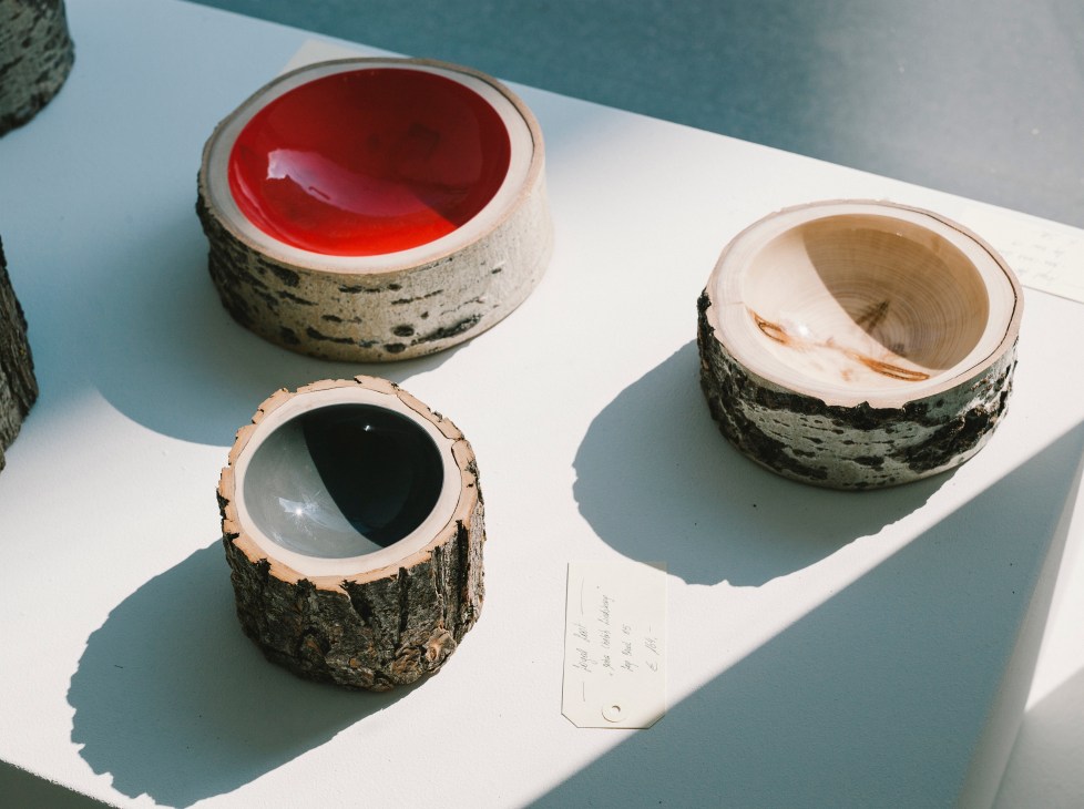 Three handcrafted ceramic vessels with natural wood-slice bodies and glazed interiors in red, natural, and dark colors.