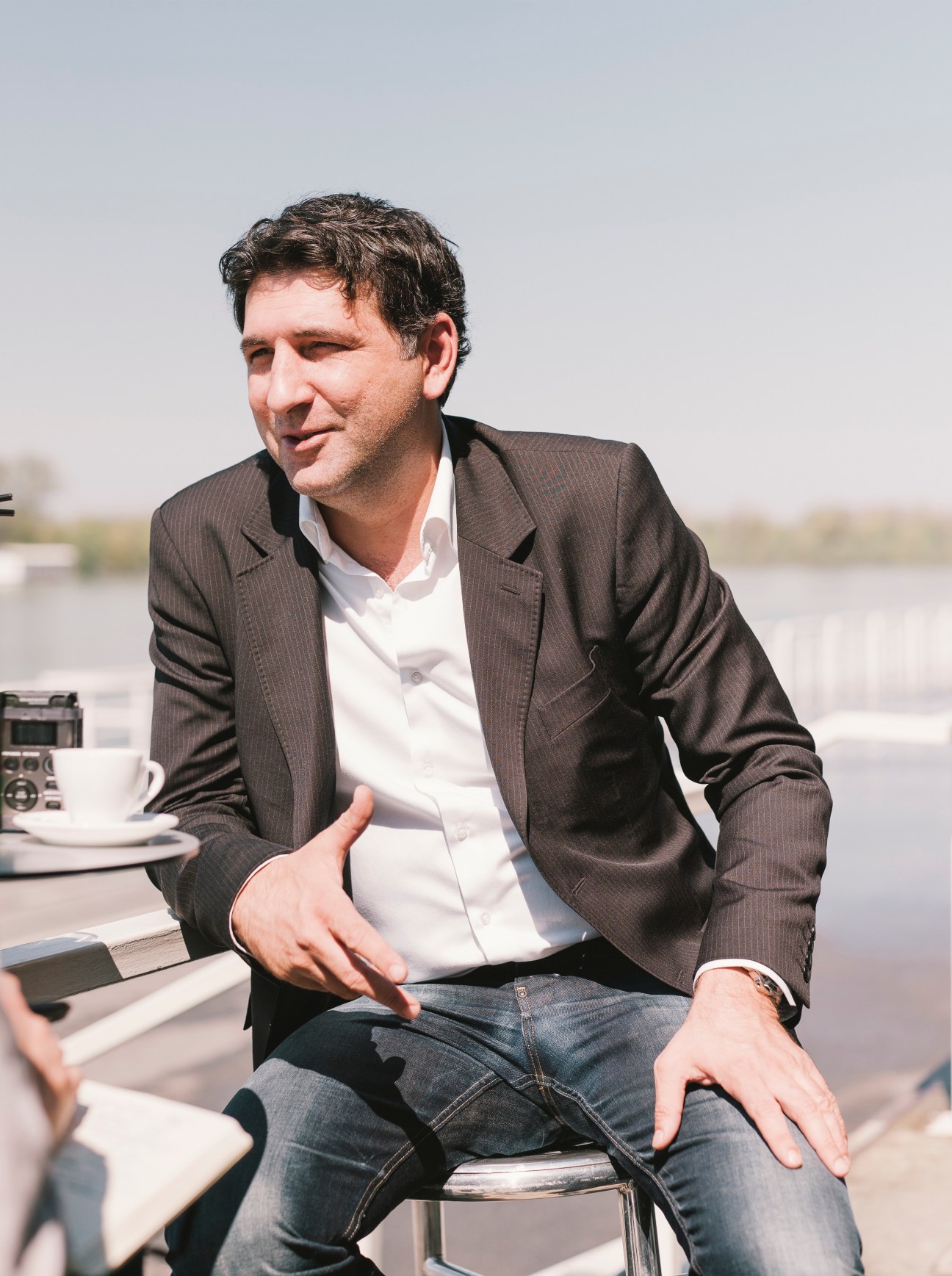 Nikola Zivanovic, restaurateur and financial consultant, sits outdoors by a river.