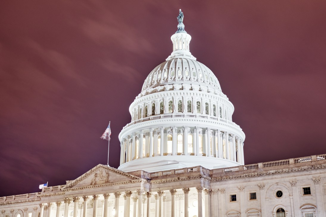 The United States Capitol building with its iconic white dome illuminated against a dramatic purple sky.