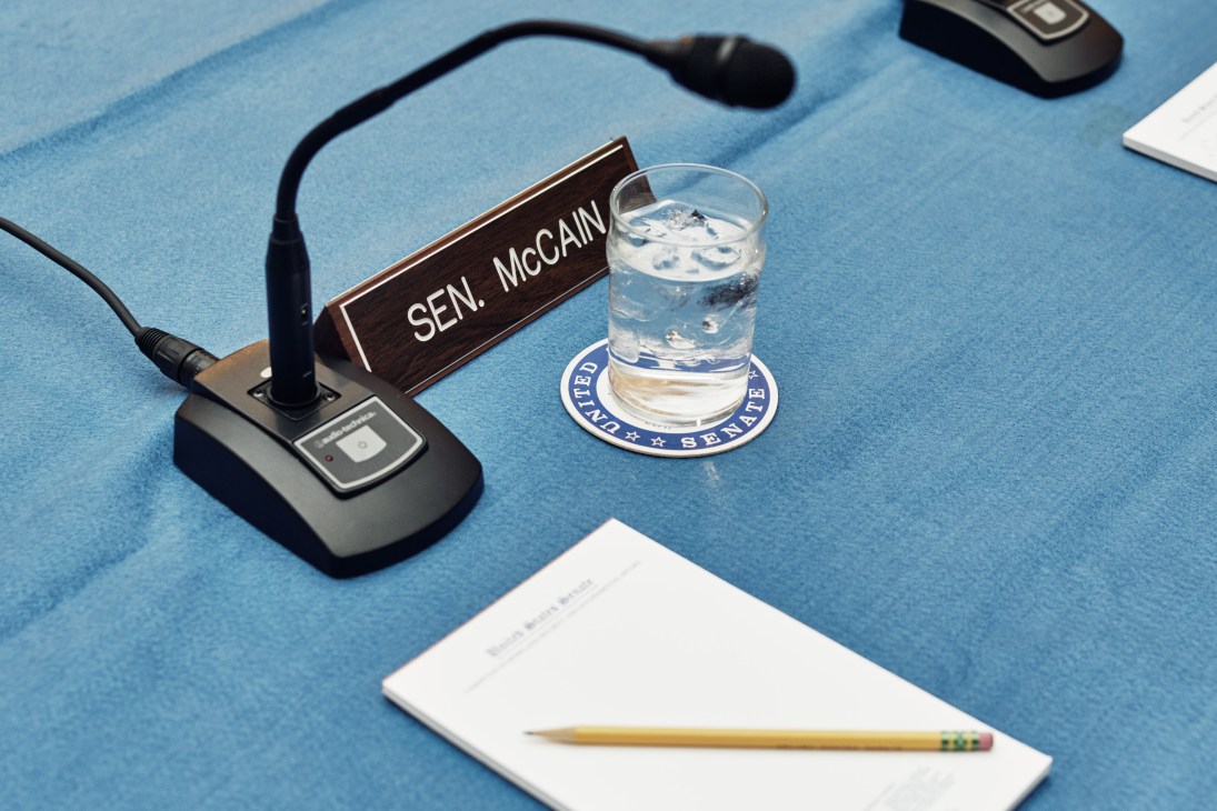 Senator McCain's nameplate and microphone at a US Senate committee desk with water glass.