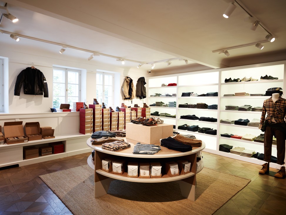 Interior of Dantendorfer shop in Salzburg with curved wooden display tables, white shelving, and clothing racks.