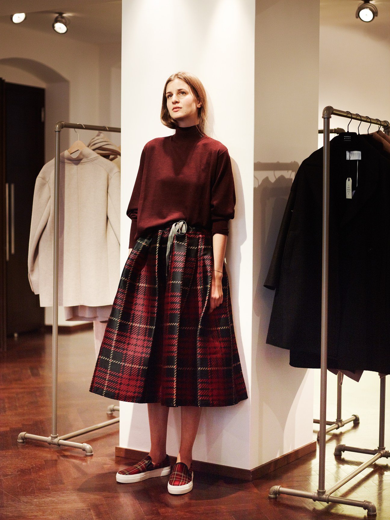Woman wearing burgundy turtleneck sweater and tartan skirt in Dantendorfer shop interior.