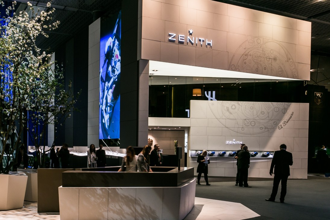 Zenith's three-storey booth at Baselworld featuring cream-coloured stone, wenge wood and smoked glass with signage and display cases.