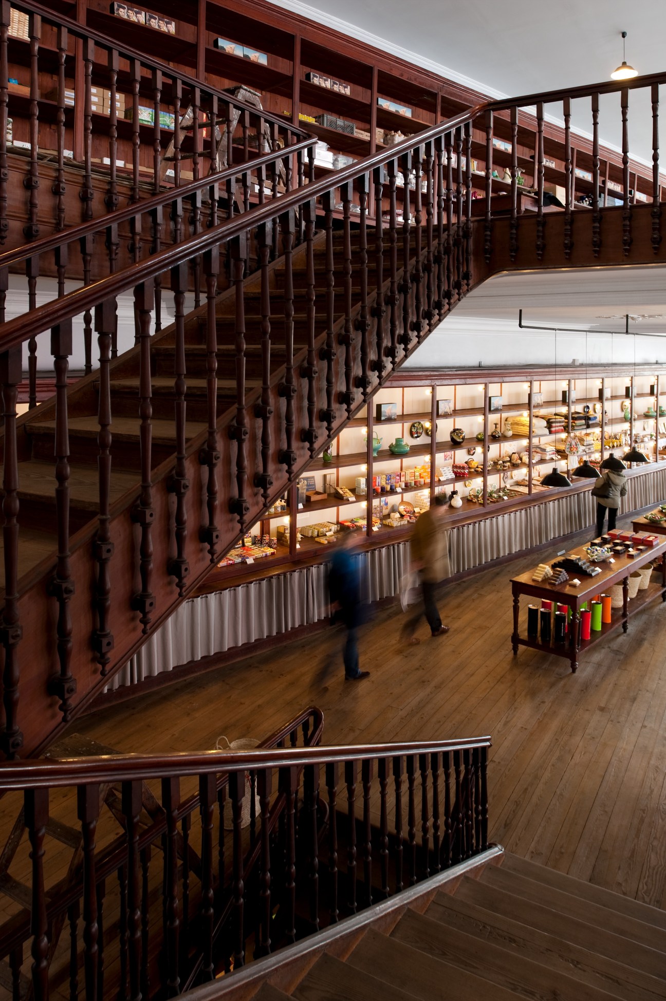Interior of A Vida Portuguesa shop showing wooden staircase, upper shelves with vintage products, and ground floor display areas.
