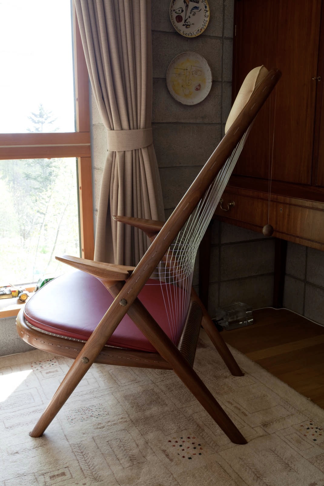 Racket Chair by Helge Vestergaard Jensen with wooden frame and string back, displayed in a sunlit room.
