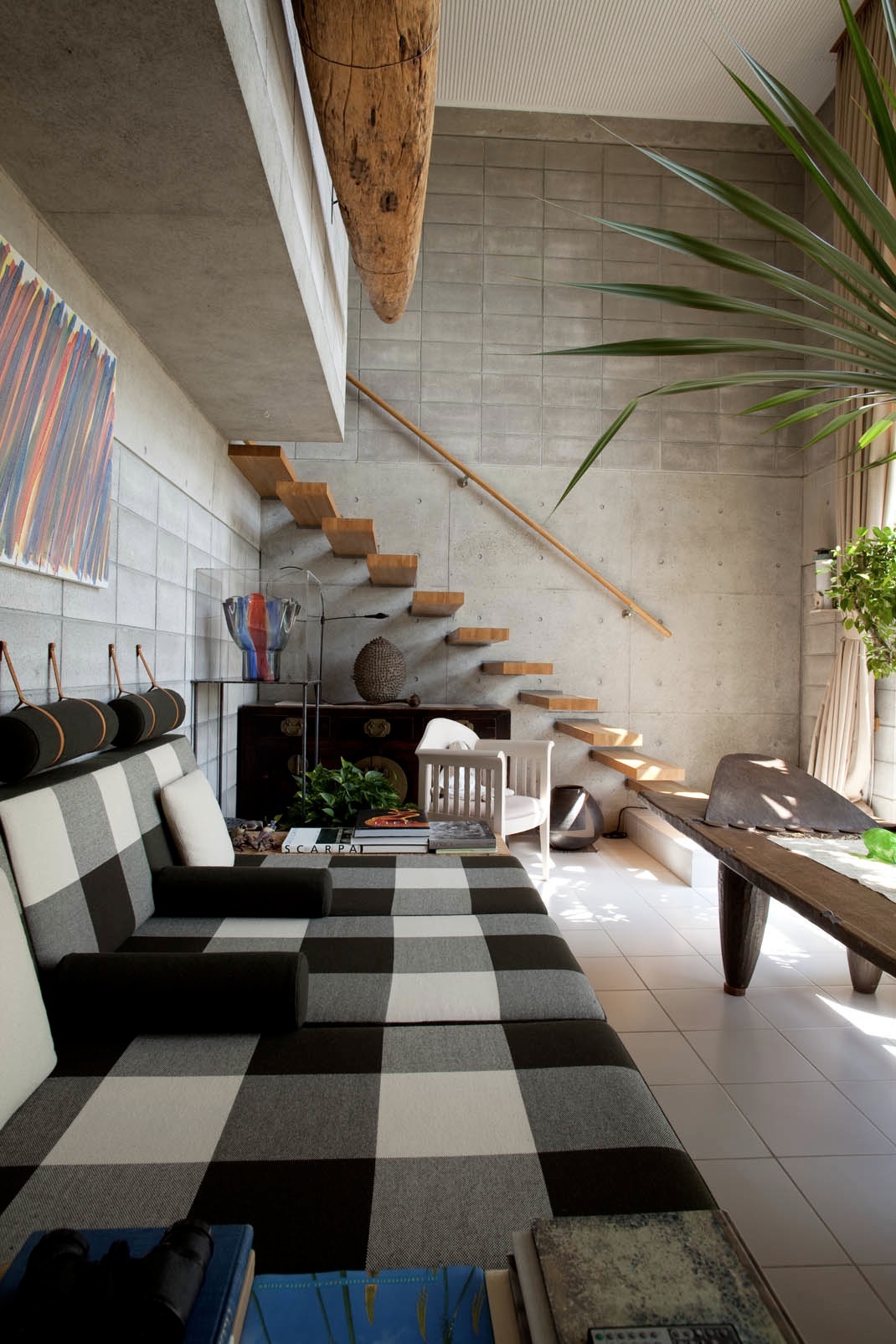 Modern interior with Børge Mogensen sofa and Eliel Saarinen chair beside wooden stairs and potted plants.