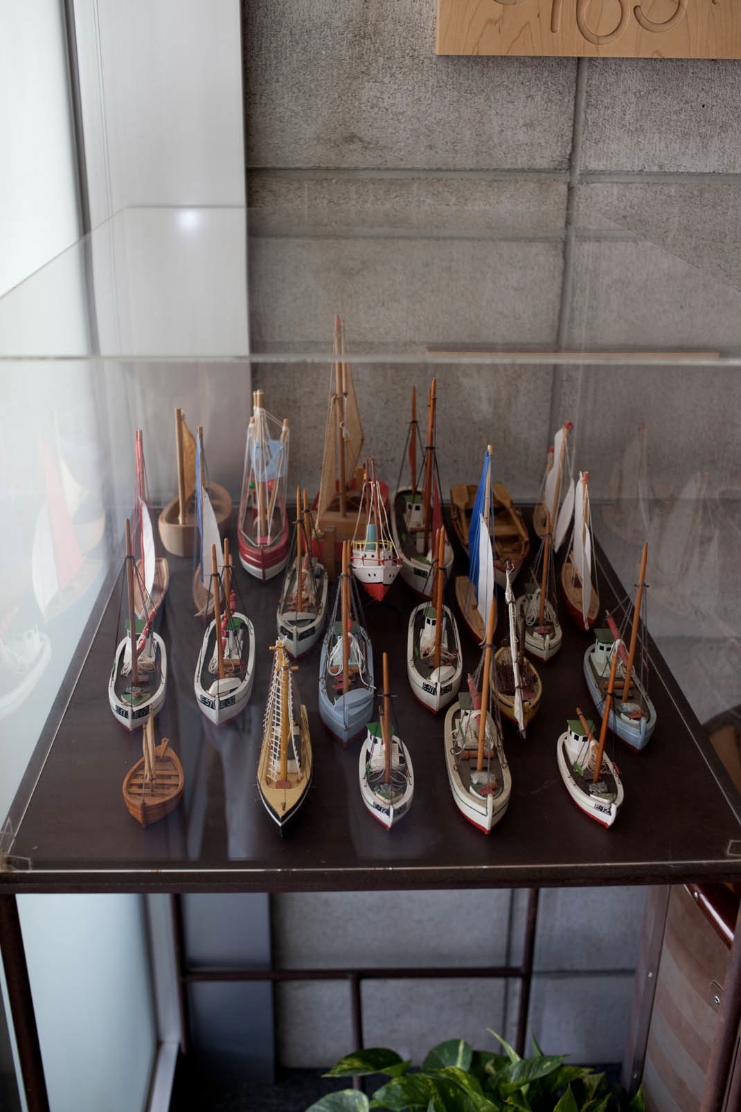 Collection of miniature model sailing ships from Denmark displayed on a black shelf.