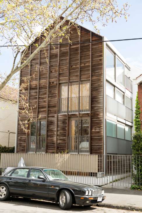 Modern wooden-clad apartment building with large windows on a Melbourne street.