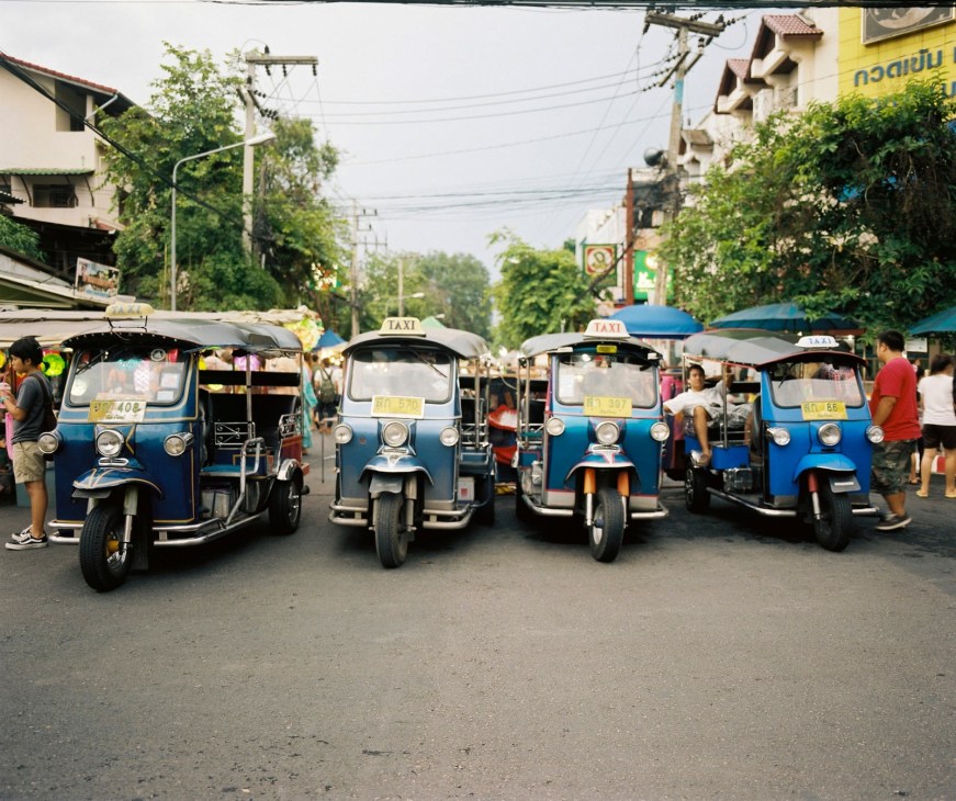 Row of blue and white tuk-tuks parked on a street near Wat Phra Singh in Chiang Mai.
