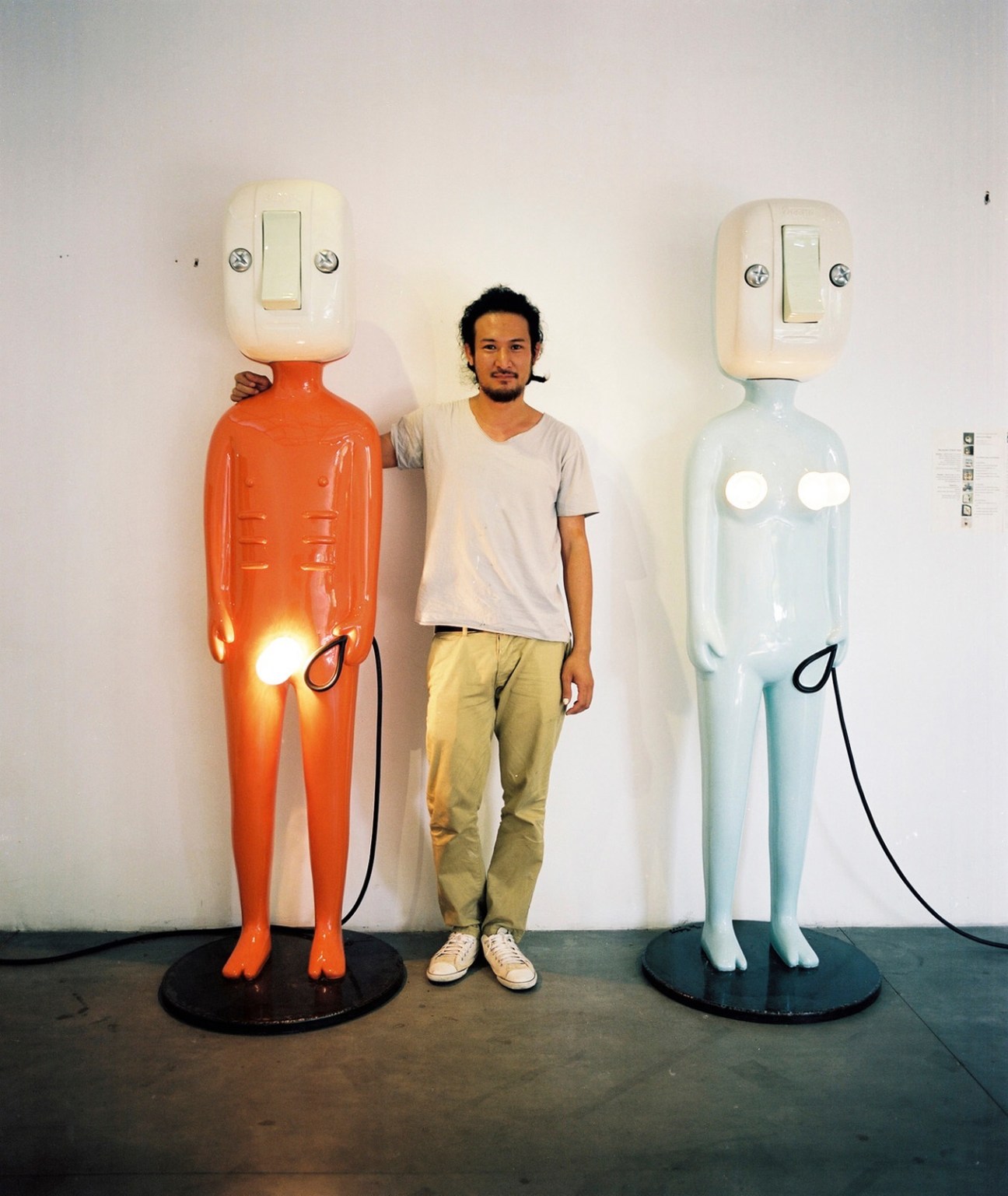 Artist Khun Hern stands between two colorful sculptural light installations at SeeScape gallery.