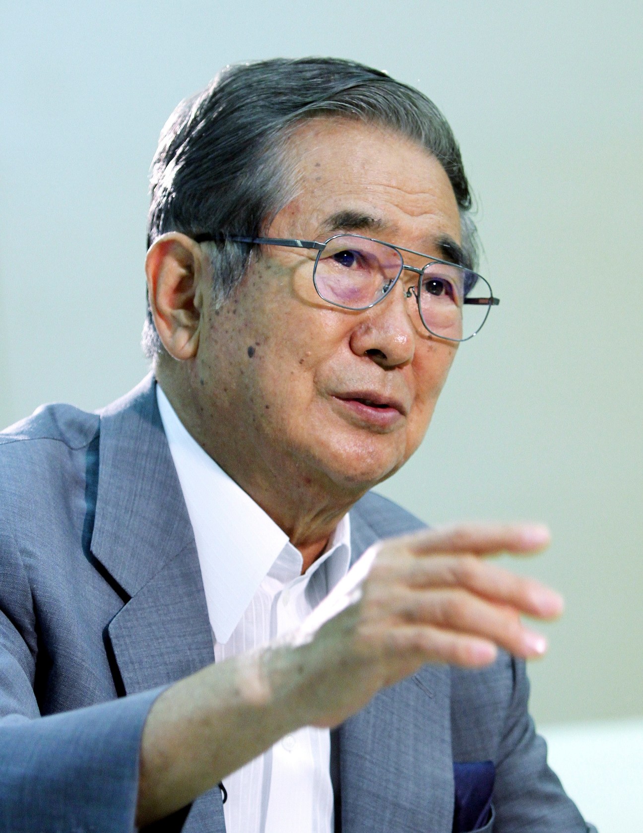 Shintaro Ishihara, Tokyo's governor, wearing glasses and a blue suit gestures while speaking.